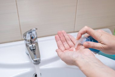 Kadın elleri, bir banyoda ellerini yıkama ve dezenfekte etme plastik şişeden eline kadar antibakteriyel sıvı sabun sıkma..
