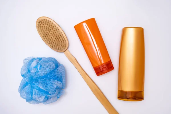 Banyo, duş aksesuarları beyaz arka planda, duş jeli, renkli plastik şişelerde vücut yıkama, ahşap fırça ve sünger..