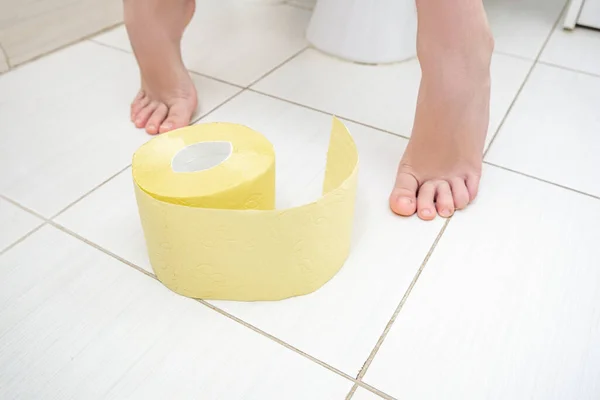Przycięte Nogi Chłopca Siedzącego Toalecie Rolką Żółtego Papieru Toaletowego Podłodze — Zdjęcie stockowe