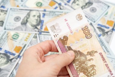 Arka planda yüz ruble ve Amerikan doları banknotları tutan bir el, ruble devalüasyon ve usd-ovuşturma oranı konsepti, bir dolara yüz ruble..