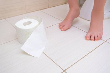 Tuvalette bir rulo tuvalet kağıdıyla oturan bir çocuğun kesilmiş bacakları, sindirim sorunları ve tuvalet kavramındaki zorluklar..
