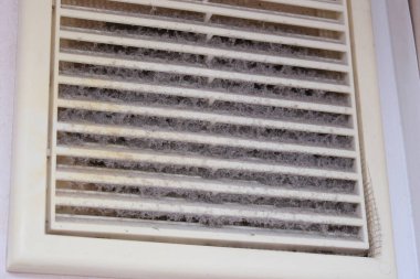 Extremely dirty and dusty white plastic ventilation air grille at home close up, harmful for health, house cleaning concept.. clipart