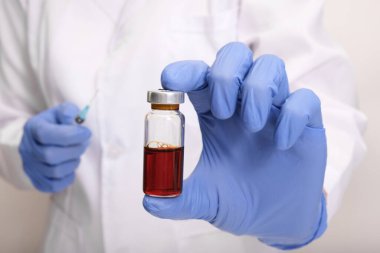 Mavi eldivenli doktor grip ve koronavirüse karşı aşı, aşı ve aşılama ampulü tutuyor..