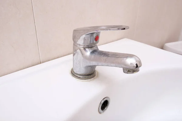 Kireç pullu kirli musluk, kireçlenmiş su musluğu, banyo lavabosunda limon tartısı, ev temizliği konsepti..
