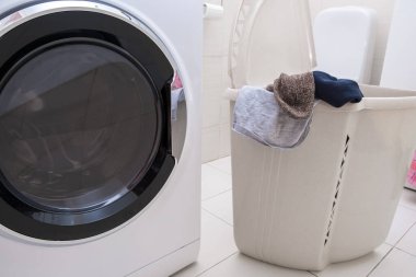 Kirli çarşaf ve kıyafetlerle dolu büyük bir çamaşır sepetinin içinde modern bir çamaşır makinesi..