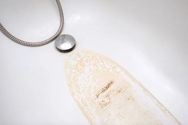 Extremely dirty bath drain mesh, hole and surface covered with limescale or lime scale and rust, cleaning calcified and rusty bathroom equipment.