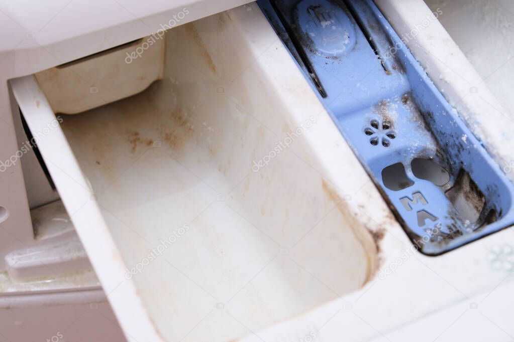 Dirty moldy washing machine detergent and fabric conditioner dispenser drawer compartment close up. Mold, rust and limescale in washing machine tray. Home appliances periodic maintenance concept.