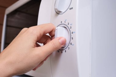 Kadın eli mikrodalga fırını hazırlamak için açar, öğle veya akşam yemeği için ısıtır, mutfak elektrikli aletleri konsept kullanır..