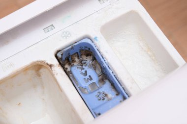 Kirli, küflü çamaşır makinesi deterjanı ve kumaş kremi kutusunun çekmecesini kapat. Küf, pas ve kireç rengi çamaşır makinesi tepsisi. Ev aletleri periyodik bakım kavramı.