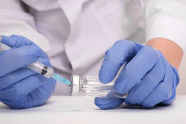 Mavi eldivenli doktor şırıngayı aşı, aşı ve grip ve koronavirüse karşı aşılama ile dolduruyor.