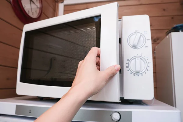 Женщина вручную открывает микроволновую печь для того, чтобы приготовить, тепло пищи на обед или ужин, кухня электроприборы с использованием концепции — стоковое фото
