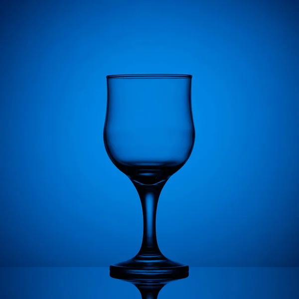Kaca anggur kosong dengan latar belakang biru — Stok Foto