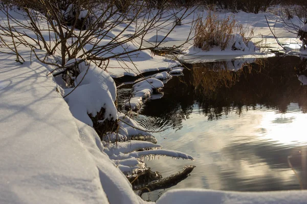 Blick von der Küste auf einen zugefrorenen Fluss mit ungewöhnlich runden Eisstücken und Bäumen an der Flussküste. Winter. schwarz-weiß — Stockfoto