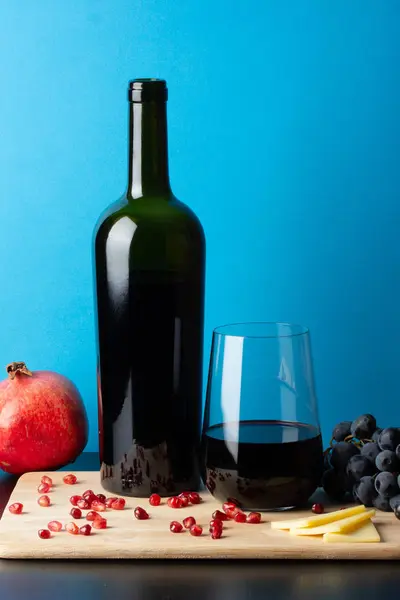 Bottle of wine with a glass, grapes, pomegranate and cheese. — Stock Photo, Image