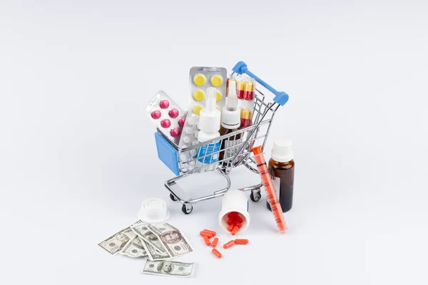 Carrito de compras con medicamentos y dinero sobre fondo blanco —  Fotos de Stock