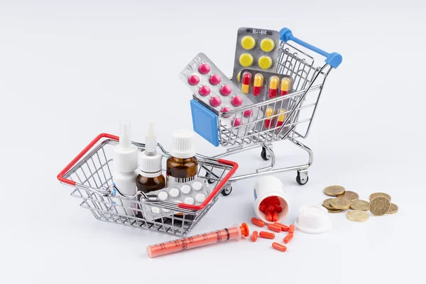 Carrinho de compras com medicamentos e dinheiro sobre fundo branco Fotos De Bancos De Imagens