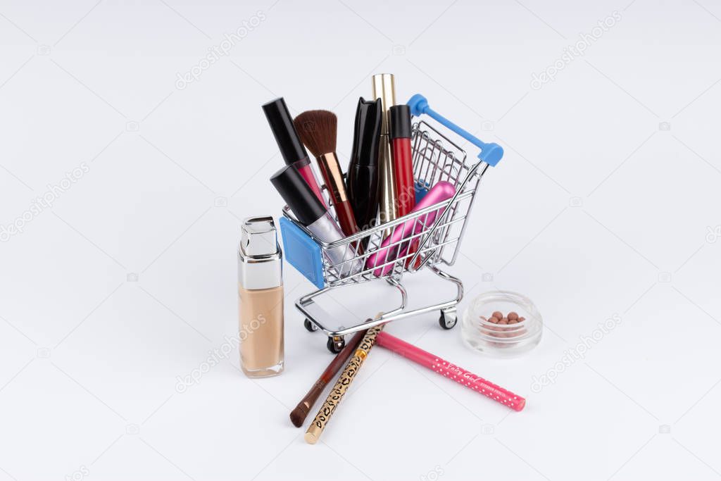 Shopping cart with cosmetics and moneys on white background