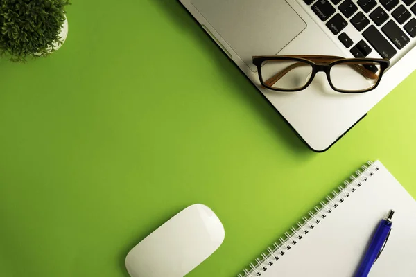 Yeşil arkaplan ofis masasındaki boş sayfa üst görünümü 