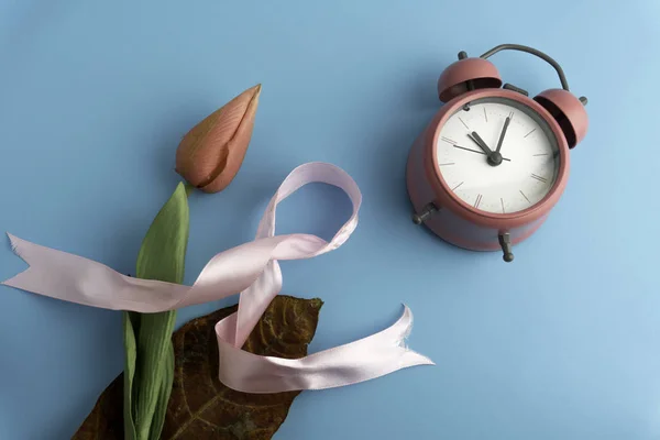 Göğüs kanseri kavramı, kurdele, zaman ve pembe çiçek izole edilmiş. — Stok fotoğraf