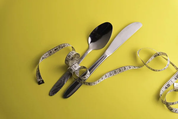 Cuchara y cuchillo con cinta métrica, dieta o alimentación saludable —  Fotos de Stock