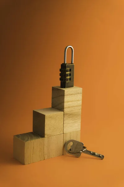 Combination padlock and key isolated on orange background.