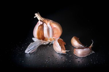 Karanlık bir arka planda sarımsağın sanatsal resmi. Sarımsaklı birkaç baş sarımsak..