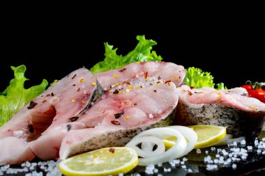 Siyah arka planda marul baharatlı ve domatesli balık bifteği