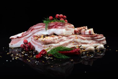 Dereotu, biber, sarımsak ve soğanla süslenmiş baharatlarla süslenmiş siyah bir zemin üzerinde et katmanları ile domuz yağı.