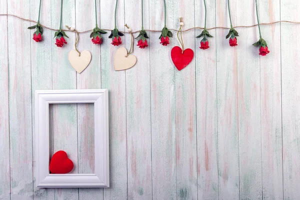 frame, roses and a garland of hearts on a light wooden background .space for text
