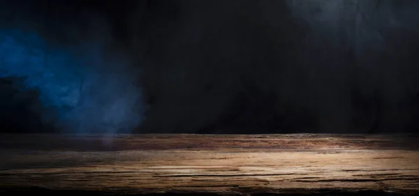 table top made of old wood with a spot of light and blue smoke in dark colors