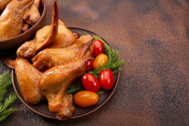 Tütsülenmiş tavuk kanadı, domatesler dokuma kaplı bir tabakta