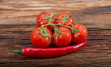 Tahta bir arka planda olgun kiraz domatesleri ve kırmızı biberler.