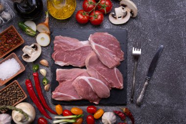 Biftekler, taze sebzeler, arka plandaki dokulu manzaraya yakın plan baharatlar.