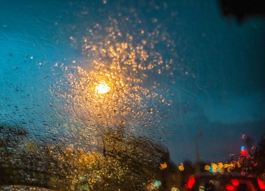 Trafik ışıkları ve şiddetli yağmur sırasında aracın cama araba farlar.