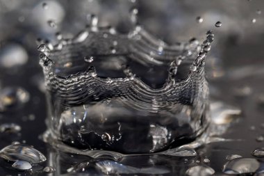 Su damlaları siyah bir yüzeye çarpıyor.