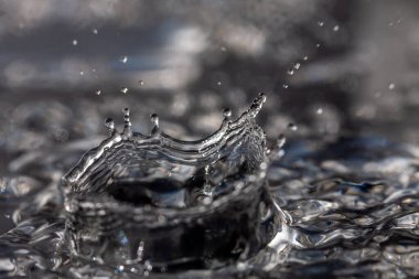 Su damlaları siyah bir yüzeye çarpıyor.