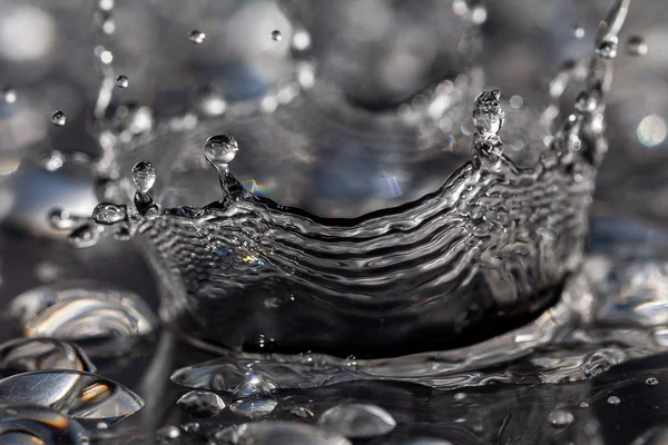 Gotas de agua golpeando contra una superficie negra . — Foto de Stock