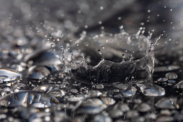 Gotas de água batendo contra uma superfície preta . — Fotografia de Stock