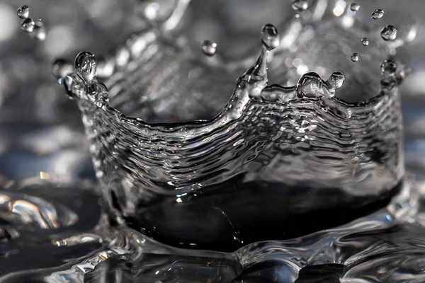 Gotas de água batendo contra uma superfície preta . — Fotografia de Stock