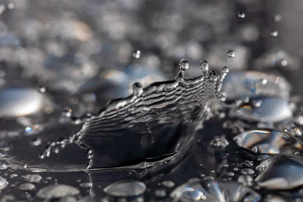 Wassertropfen treffen auf schwarze Oberfläche. — Stockfoto