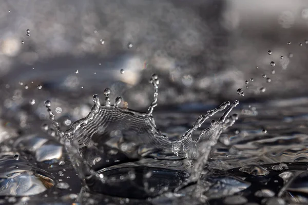 Gotas de agua golpeando contra una superficie negra . — Foto de Stock