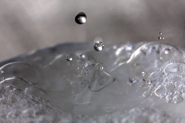 Gouttes d'eau tombant sur la surface d'un verre plein de liquide . — Photo