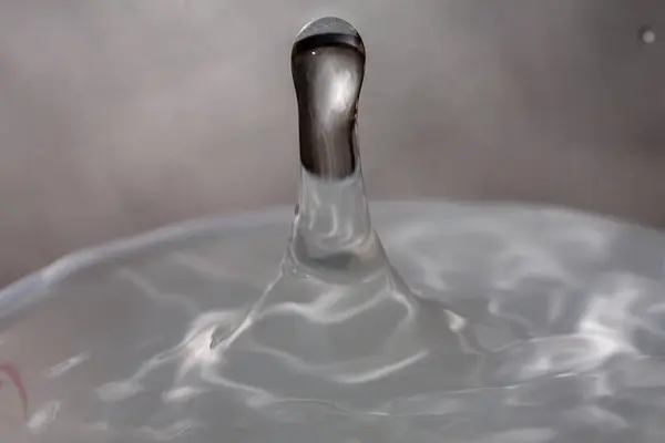 액체가 가득 한 유리잔 의표 면 위로 물방울이 떨어진다. — 스톡 사진