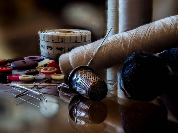 Still life of sewing items on a glass background.