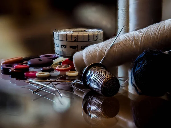 Still life of sewing items on a glass background.