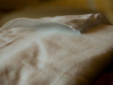 Katlanmış masa örtüsü, şeffaf cam bir masaya yansıyor..