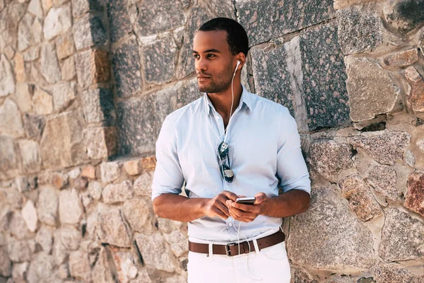 Hombre con móvil en auriculares escuchando música — Foto de Stock