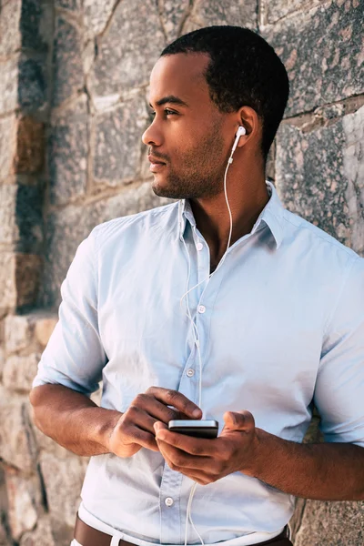 Uomo con cellulare in cuffia ascoltare musica — Foto Stock