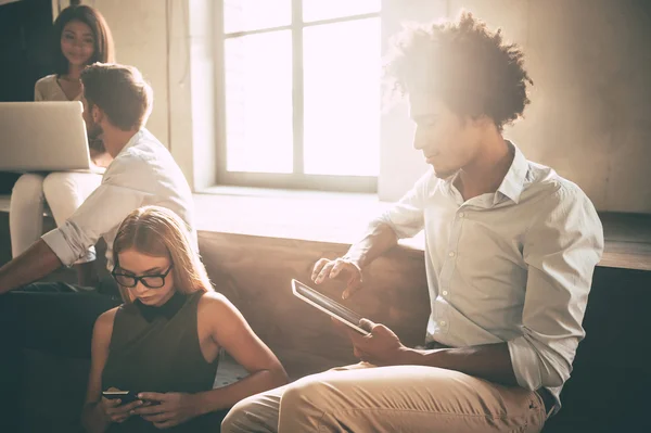 Young people holding different gadgets — Stock fotografie