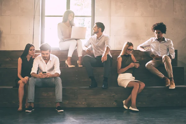 Jovens segurando diferentes gadgets — Fotografia de Stock